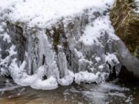 Mehrarmige Eisgebilde mit Neuschneeauflage an Felsen im Lochgrabenbach
